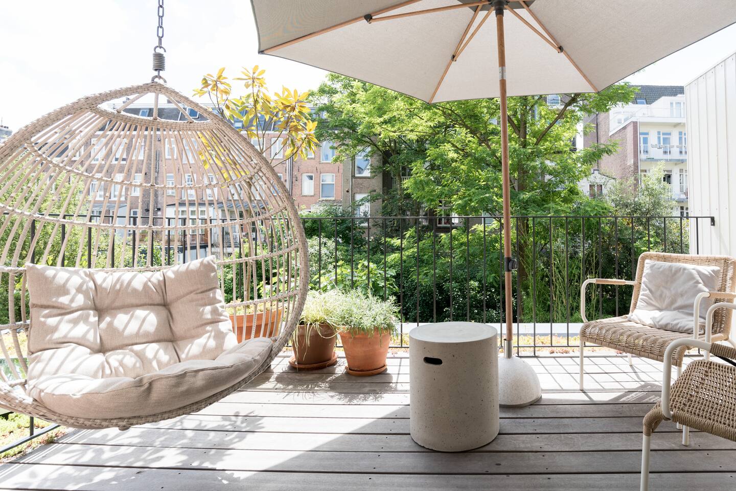Het terras van de tuinsuite met hangstoel en groene binnentuin